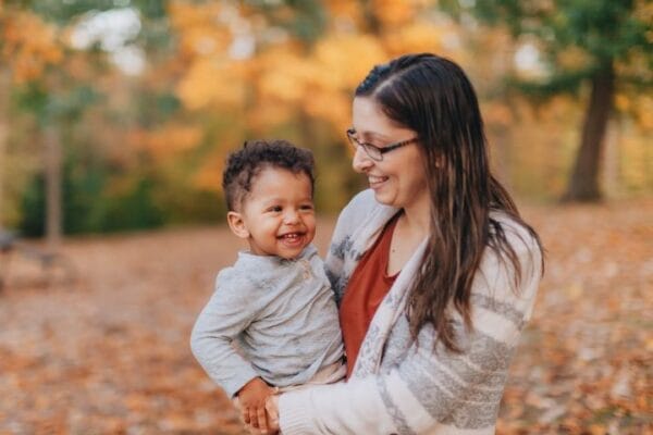 A woman smiles at a child she holds in her arms.